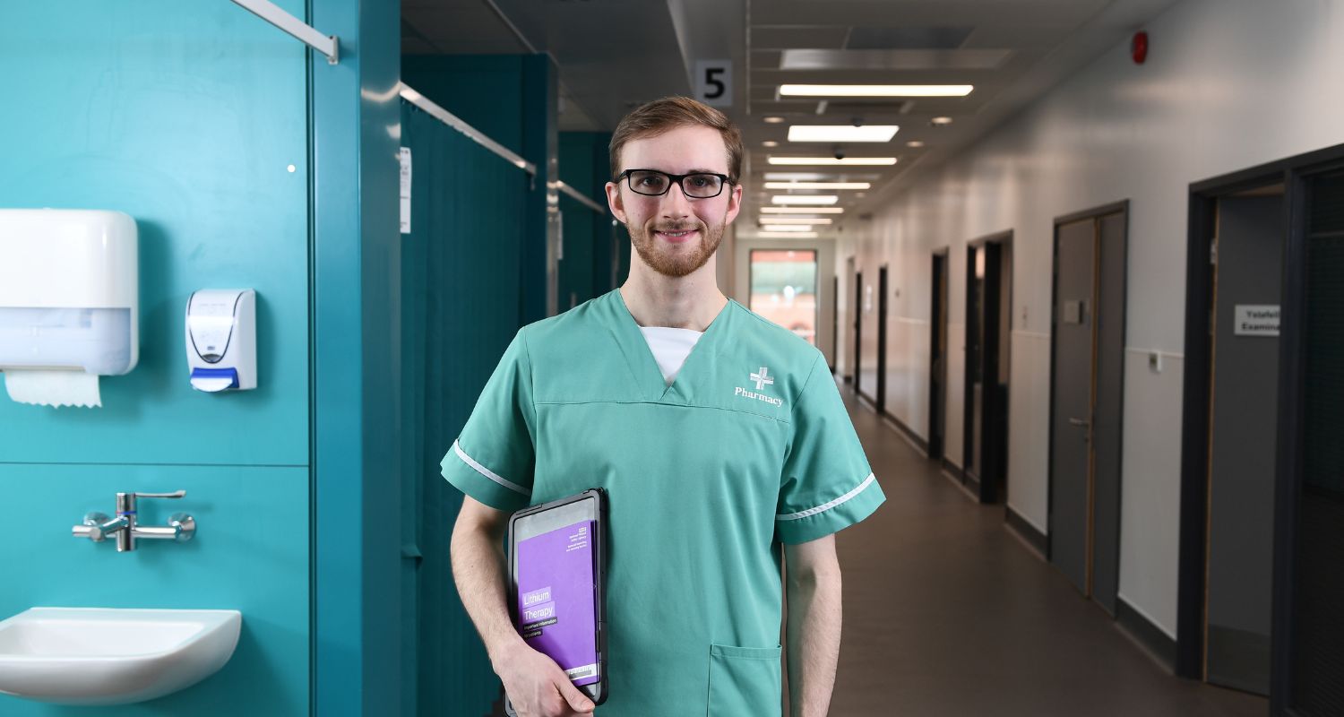 a healthcare professional in scrubs standing at the end of a hospital hallway