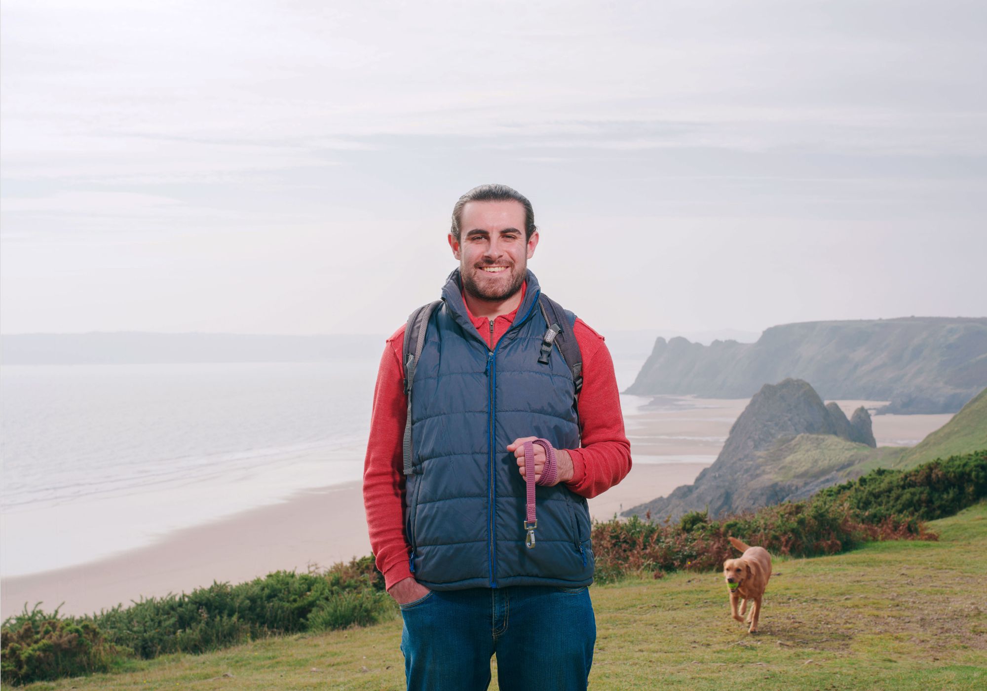 Man walking his dog in the welsh countryside, near the beach