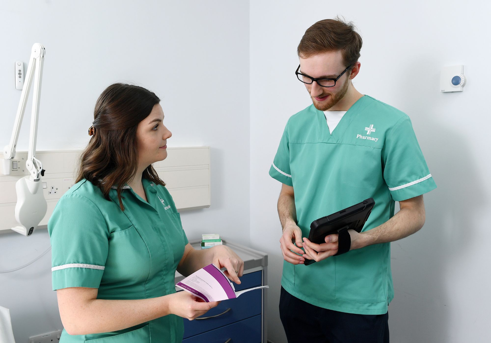 two healthcare professionals in scrubs talking to each other